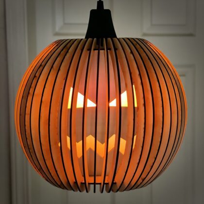 DIY pumpkin lamp kit by Encinitas 3D with a glowing LED flicker bulb inside, showcasing a cut-out face surrounded by 50 rounded ribs.