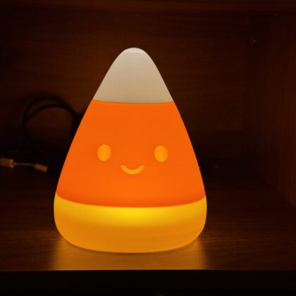 Candy corn lamp glowing orange and yellow with a smiling face